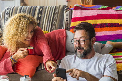 Midsection of man using mobile phone while sitting on sofa