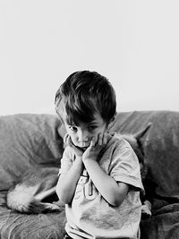 Portrait of boy with hand on chin sitting at home