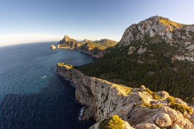 Scenic view of sea by cliff against sky