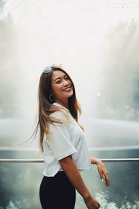 Portrait of smiling woman standing by railing