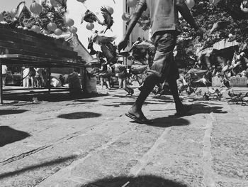 Low section of people walking on street in city