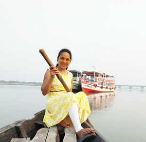 Portrait of smiling young woman standing against sky