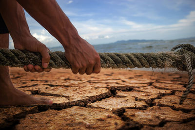 Close-up of hand holding sand at beach against sky