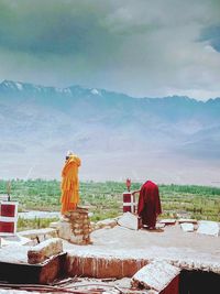 Man on cross against mountains against sky