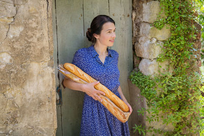 Young woman standing with french baguettes in the countryside