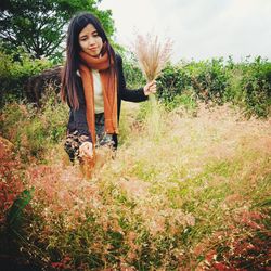 Portrait of smiling young woman standing against trees