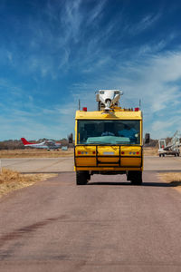 Yellow cart on road against sky