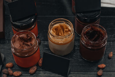 Handmade chocolate spread or nougat cream on glass jar on wooden rustic background with cacao beans.