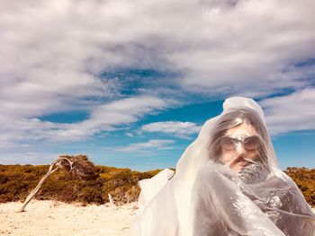 Portrait of woman face covered in plastic against cloudy sky