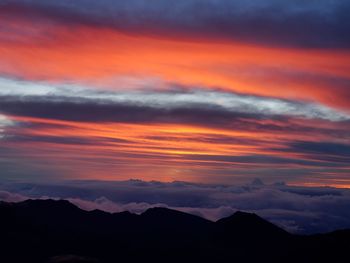 Scenic view of silhouette mountains against orange sky