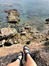 Low section of woman on rock by sea