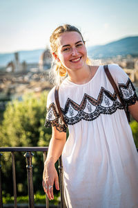 Portrait of smiling young woman standing against sky