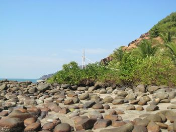 Rocks on beach against clear blue sky