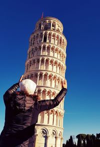 Optical illusion of woman holding pisa tower against blue sky