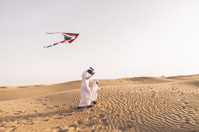 Full length of father with son flying kite in desert