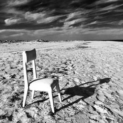 Empty chairs on beach against sky