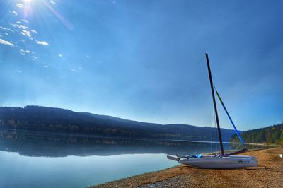 Sailboats moored on lake against sky