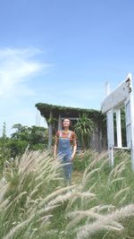 Portrait of woman standing by plants against sky