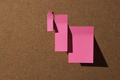 Pink office sticky notes on cork board with hard shadow with copy space