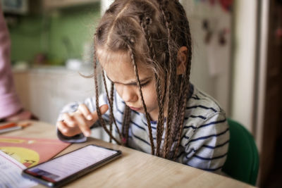 Pretty stylish schoolgirl studying math during her online lesson at home, online education concept