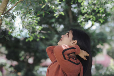 Side view of woman standing against trees