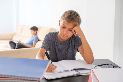 Rear view of boy sitting on table