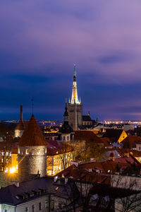 Illuminated buildings in city against sky at sunset