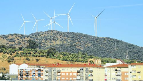 Traditional windmill by building against sky