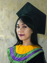 Portrait of a smiling young woman standing against wall