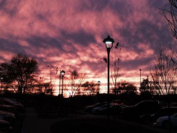 Silhouette cars on street against sky at sunset