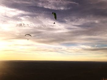 Silhouette person paragliding during sunset