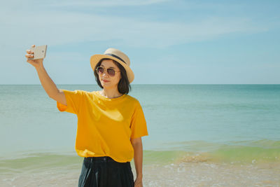 Woman taking selfie from phone against sea