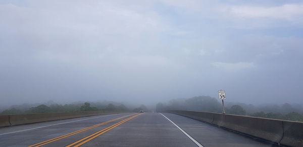 Empty road against foggy sky