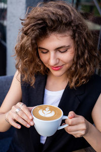 Portrait of smiling young woman drinking cappuccino