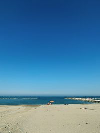 Scenic view of beach against clear blue sky