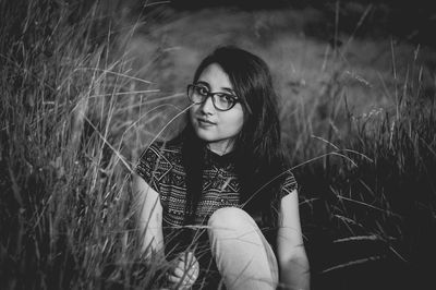 Young woman sitting amidst grass on field