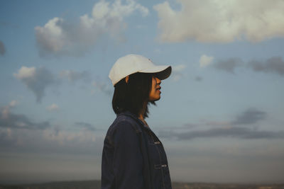 Side view of woman looking away against sky