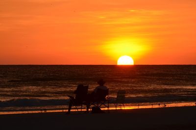 People sitting on beach during sunset