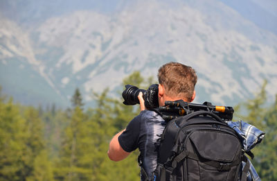Rear view of male hiker photographing with camera
