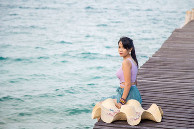 Portrait asian woman in a purple bra sitting on a wooden bridge on the beach