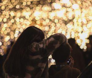 Rear view of couple kissing at night