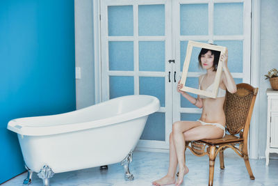 Portrait of young woman sitting on chair at home