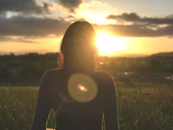 Woman photographing on field at sunset