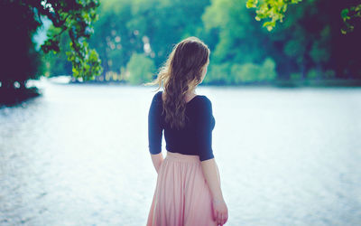 Rear view of woman standing by lake