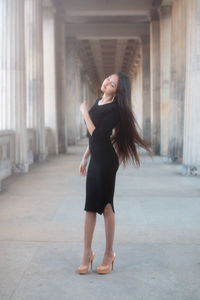 Full length of woman standing against in colonnade