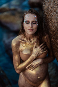 Portrait of shirtless young woman standing outdoors