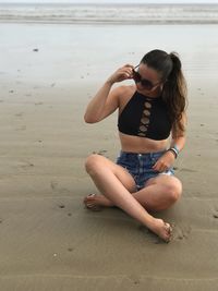 Young woman sitting on sand at beach