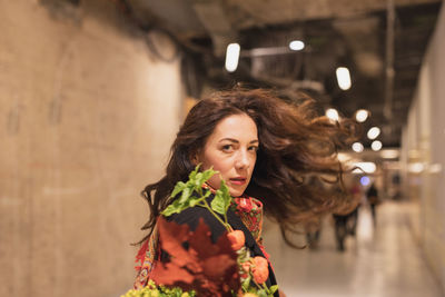 Portrait of woman holding plant while standing in tunnel