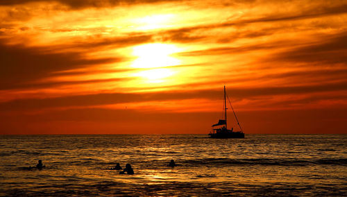 Silhouette sailboat in sea against sky during sunset