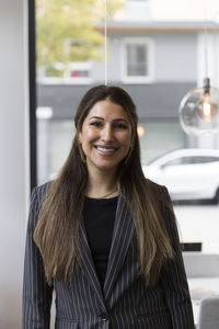 Portrait of smiling female real estate agent wearing blazer standing in office